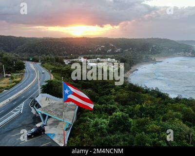 Une photo aérienne du drapeau de Porto Rico qui agite dans l'air à un coucher de soleil doré à Quebradillas Banque D'Images