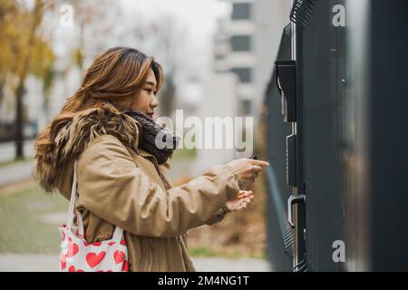 Jeune femme entrant le code à la porte dans la zone urbaine Banque D'Images