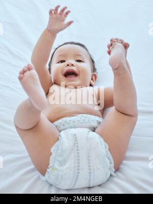 Laisse jouer. une adorable petite fille couchée seule sur un lit à la maison. Banque D'Images