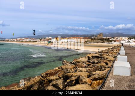 Des kitesurfers survolant l'océan près de la plage avec la ville de Tarifa en arrière-plan. Andalousie, Espagne. Jour de printemps ensoleillé et venteux. Banque D'Images