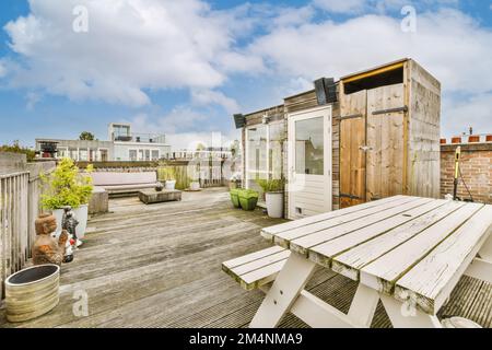 une zone extérieure avec terrasse en bois et bancs blancs sur le côté droit de la photo, il y a un ciel bleu dans le Banque D'Images