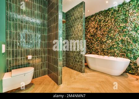 salle de bains avec carrelage vert sur les murs et parquet autour de la baignoire, des toilettes et de la baignoire Banque D'Images