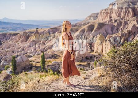 Jeune femme explorant la vallée avec des formations rocheuses et des grottes de fées près de Goreme en Cappadoce Turquie Banque D'Images