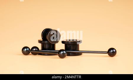 tunnels noirs métalliques , accessoires de perçage d'oreilles et de langue. Banque D'Images