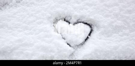 Heart shape love sign, drawn on a snow-covered ice with copy space. Hand drawn heart shape in the fresh snow. Symbol of love in winter holiday season Stock Photo