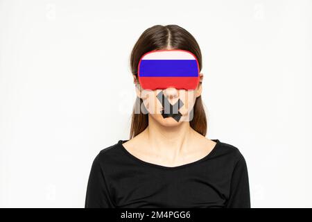 Une fille avec un bandeau dans la couleur du drapeau de la Russie et un aide-bande a fermé la bouche sur un fond blanc, une fille russe ne voit pas ou n'entend pas, Banque D'Images