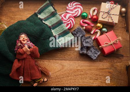 Le Befana au charbon doux et aux bonbons sur fond de bois. Tradition italienne d'Epiphanie Banque D'Images