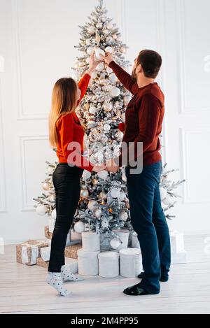 Vacances d'hiver et les gens concept - heureux couple decorating Christmas Tree at home Banque D'Images