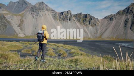 Homme voyageur à la recherche de montagnes fantastiques sur les dunes de sable de lave volcanique sur la plage Stokksness, Islande Banque D'Images