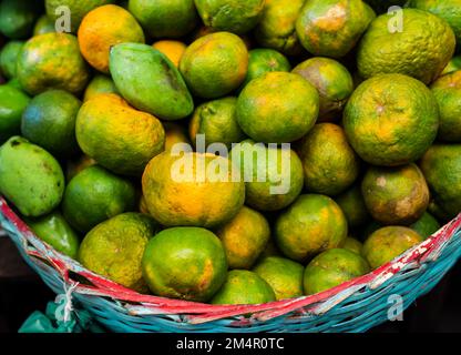 Mandarines vertes empilées dans un panier prêt à la vente au salon. Concept organique. Banque D'Images