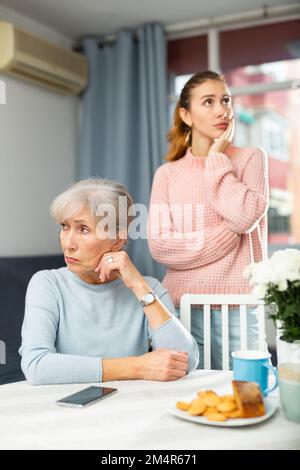 Bouleverser la femme âgée à la table après s'être querelle avec la fille adulte Banque D'Images