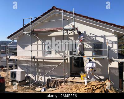 Fischbach, Allemagne - 8 mars 2022: Nouveau site de construction avec plâtre de base fini, ouvrier à l'échafaudage. Banque D'Images