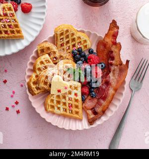 Petit déjeuner pour la Saint-Valentin pour deux avec gaufres en forme de coeur sur le rose, vue du dessus Banque D'Images