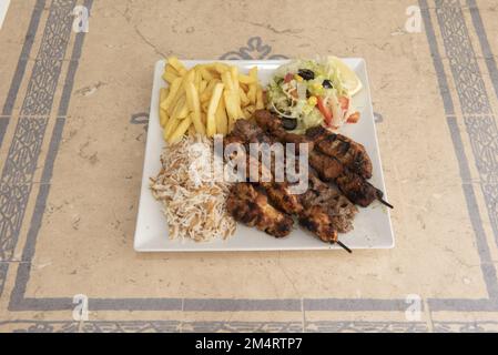 Brochettes typiques du Moyen-Orient de viande de kebab avec riz, salade turque et frites surgelées Banque D'Images