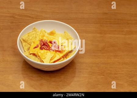 Un bol de nachos de maïs mexicain avec sauce cheddar et morceaux de bacon frits Banque D'Images