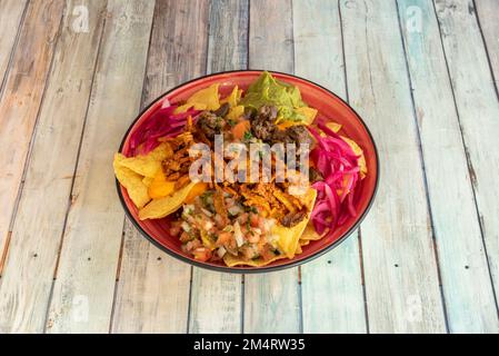 Un bol de nachos de maïs mexicain au fromage cheddar, poulet râpé, guacamole, ragoût de cochinita pibil avec oignon rouge et pico de gallo Banque D'Images