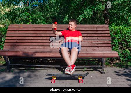 Garçon assis sur le banc et communique par chat vidéo à l'aide d'un smartphone et d'Internet. Banque D'Images