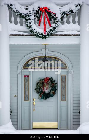 Porte avant dorée et blanche décorée de décorations de Noël et de neige, verticale Banque D'Images