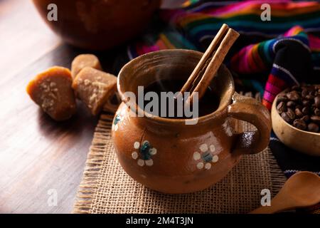 Authentique café mexicain fait maison (café de olla) servi dans une tasse traditionnelle en argile artisanale (Jarrito de barro) sur une table rustique en bois. Banque D'Images