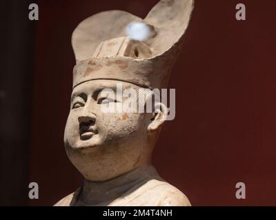 Un gros plan de la figurine d'argile blanche d'un homme d'Asie de l'est sur fond marron Banque D'Images