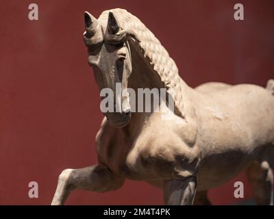 Un gros plan de la figurine d'argile blanche et brune d'un cheval d'Asie de l'est sur fond marron Banque D'Images