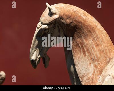 Un gros plan de la figurine d'argile blanche et brune d'un cheval d'Asie de l'est sur fond marron Banque D'Images