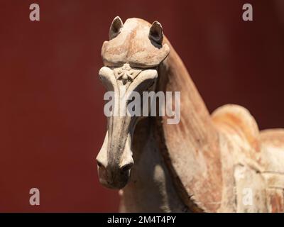 Un gros plan de la figurine d'argile blanche et brune d'un cheval d'Asie de l'est sur fond marron Banque D'Images