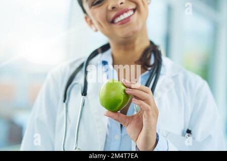 Ces nutriments sont essentiels à la santé et au maintien de votre corps. Portrait d'une jeune femme médecin tenant une pomme. Banque D'Images