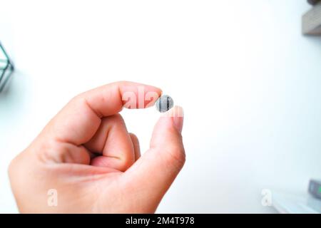Pile bouton ou pile bouton LR1130 en main, objet isolé sur fond blanc Banque D'Images