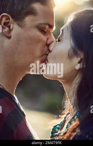 L'amour est la plus grande histoire à quatre lettres. un jeune couple affectueux qui embrasse l'extérieur. Banque D'Images