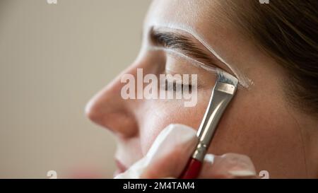 Le maître dessine la forme des sourcils avec de la peinture blanche avant de colorer. Banque D'Images