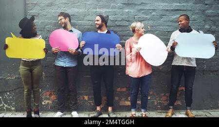 Écoutez, j'ai eu quelque chose à dire. un groupe diversifié de personnes tenant des bulles de la parole contre un mur de briques grises. Banque D'Images