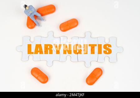 Concept médical. Sur la surface blanche de la tablette, une figure humaine miniature et des puzzles avec l'inscription - laryngite Banque D'Images