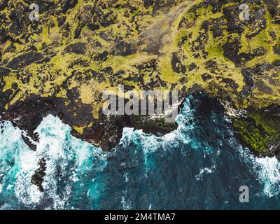 Vue de haut en bas sur une falaise et des vagues écrasant sur la côte volcanique rocheuse le jour de l'automne Banque D'Images