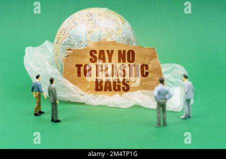 Concept écologique. Sur un fond vert sur un sac en plastique se trouve un globe et un signe avec l'inscription - DIRE NON AUX SACS EN PLASTIQUE. Figure quasi-hors foyer Banque D'Images