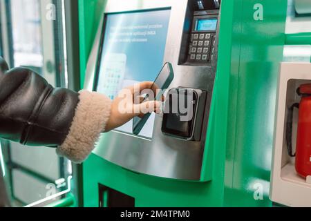 Paiement par carte sans contact sans fil. Une jeune femme de race blanche prend son billet de voyage rempli d'un terminal. Fille payant sans concession avec carte bancaire pour Banque D'Images