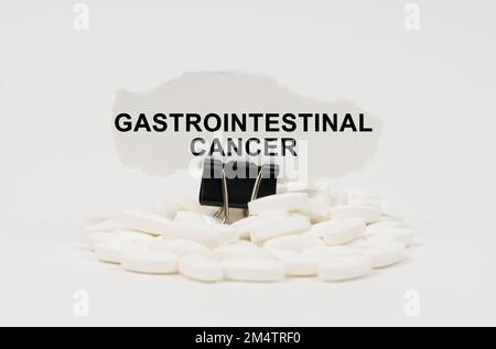 Concept médical. Sur une surface blanche sont des pilules et du papier déchiré avec l'inscription - cancer gastro-intestinal Banque D'Images