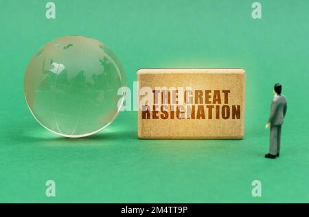 Concept d'entreprise et d'industrie. Sur la surface verte se trouve un globe et une figurine d'un homme qui regarde un signe avec l'inscription - LE GRAND RESIGNATIO Banque D'Images