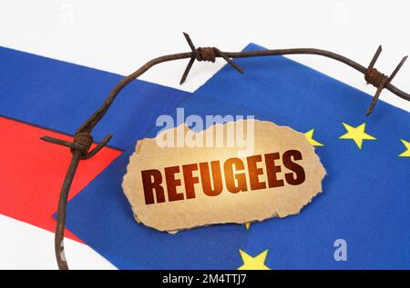 Concept politique. Sur les drapeaux de l'Union européenne et de la Russie se trouve une plaque de carton avec l'inscription - réfugiés. Drapeaux séparés par un barbelé Banque D'Images