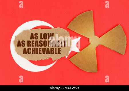 Le concept de l'industrie et de la radiation. Sur le drapeau de la Turquie, le symbole de radioactivité et de carton déchiré avec l'inscription - aussi bas que Reasonab Banque D'Images