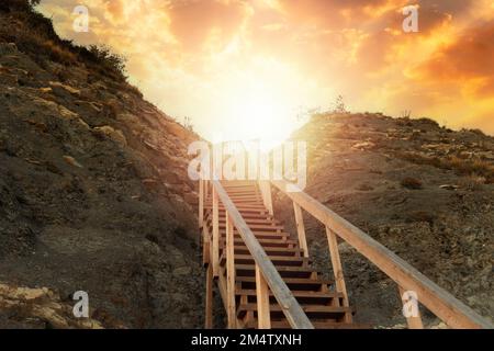 Religion et motivation. Un escalier en bois raide dans la montagne menant au ciel, avec la lumière du soleil et le coucher du soleil. Vue de dessous. Le concept de par Banque D'Images