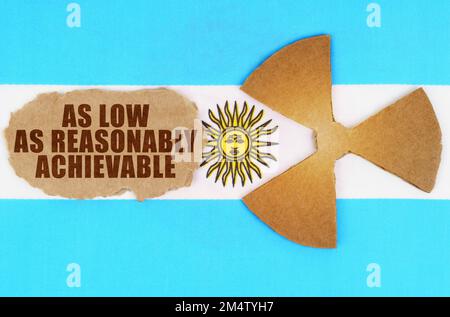 Le concept de l'industrie et de la radiation. Sur le drapeau de l'Argentine, le symbole de radioactivité et de carton déchiré avec l'inscription - As Low As Reaso Banque D'Images