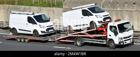 Fourgonnette de transport blanc Ford transportée sur un transporteur de véhicules commerciaux et tractant une deuxième fourgonnette de transport blanc Ford chargée sur une remorque sur l'autoroute britannique Banque D'Images