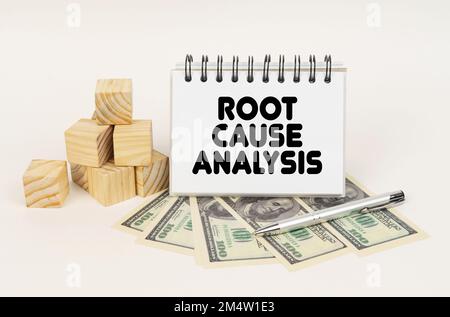 Concept d'entreprise. Sur une surface blanche, des cubes, des dollars, un stylo et un bloc-notes avec l'inscription - analyse des causes fondamentales Banque D'Images