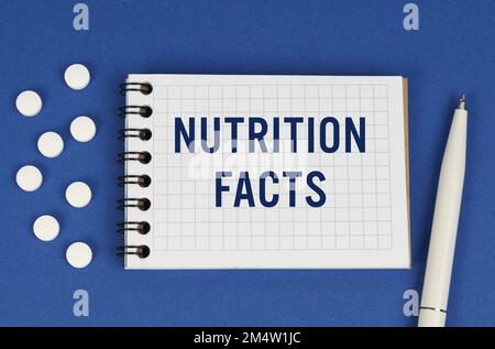 Concept médical. Sur fond bleu, un stylo, des tablettes et un bloc-notes avec l'inscription - LES FAITS NUTRITIONNELS Banque D'Images