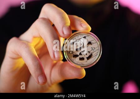 pièce de monnaie de yuan d'argent avec des pandas sur la face obverse valeur 10 tenu dans la main de la personne dans le fond Banque D'Images