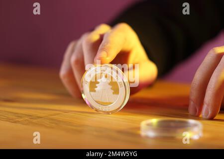 monnaie chinoise d'argent 10 yuan sous le doigt sur la table avec l'inverse contre le fond d'un mur coloré Banque D'Images