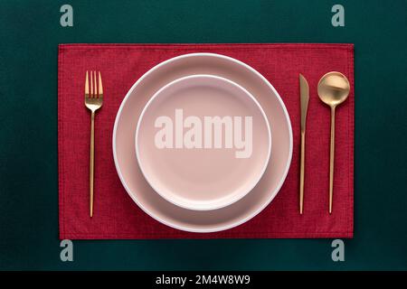 Vider la plaque avec la fourchette et le couteau sur la table vert foncé. Cadre festif avec serviette rouge et couverts dorés. Vue de dessus. Table à manger dans le restaurant. Voiture Banque D'Images