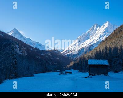 Val d'Herens, Suisse - 10 avril 2022 : vue d'hiver matinale depuis une vallée à l'ombre vers des sommets alpins ensoleillées Banque D'Images