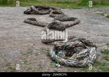 Une vieille corde épaisse d'amarrage se trouve sur le sol sur le bord de mer Banque D'Images